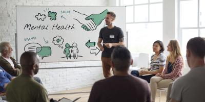 A man presenting to several people about mental health