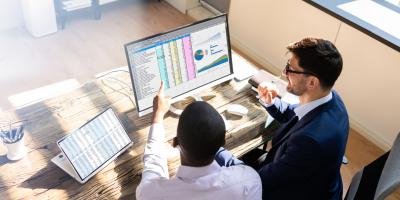 Two men talking in front of a computer